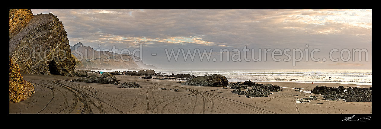 Image of Marokopa beach - wild west coast with people surf fishing. 4wd tyre tracks in black iron sand. Looking south to Te Ruaoteata Point. Moody panorama, Marokopa, Waitomo District, Waikato Region, New Zealand (NZ) stock photo image