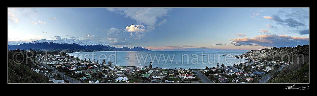 Image of Kaikoura township and bay at dusk in winter with snow on the Seaward Kaikoura Ranges at left. Panorama, Kaikoura, Kaikoura District, Canterbury Region, New Zealand (NZ) stock photo image