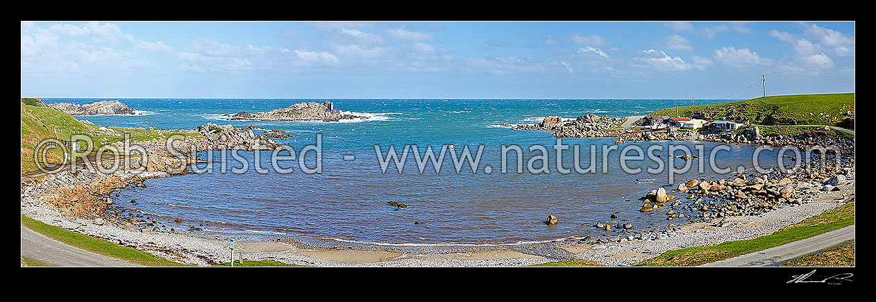 Image of Cosy Nook village nestled into a natural harbour on the Southen Scenic Route near Colac Bay. Small historic fishing village with cribs / baches. Panorama, Cosy Nook, Southland District, Southland Region, New Zealand (NZ) stock photo image