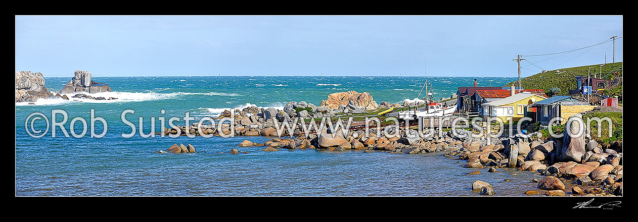 Image of Cosy Nook village nestled into a natural harbour on the Southen Scenic Route near Colac Bay. Small historic fishing village with cribs / baches. Panorama, Cosy Nook, Southland District, Southland Region, New Zealand (NZ) stock photo image