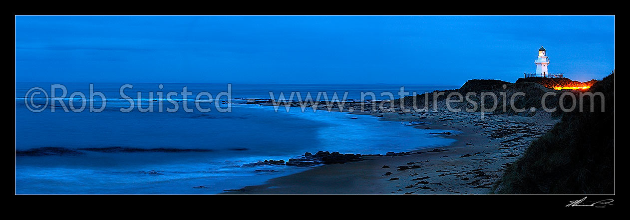 Image of Waipapa Point lighthouse and beach panorama on a moody evening. Car headlights near lighthouse, Fortrose, Southland District, Southland Region, New Zealand (NZ) stock photo image