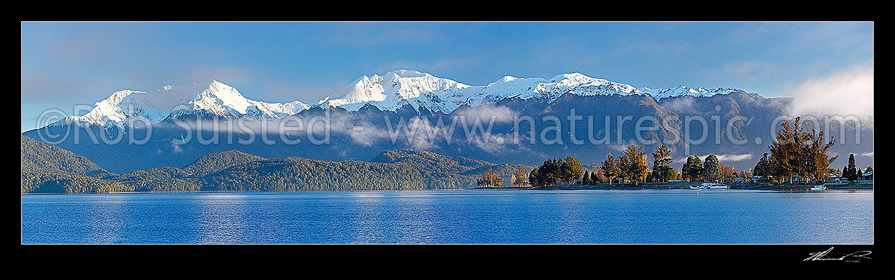 Image of Lake Te Anau and Te Anau township, with winter snow capped Murchison Mountains and Fiordland National Park beyond. Early morning panorama, Te Anau, Southland District, Southland Region, New Zealand (NZ) stock photo image