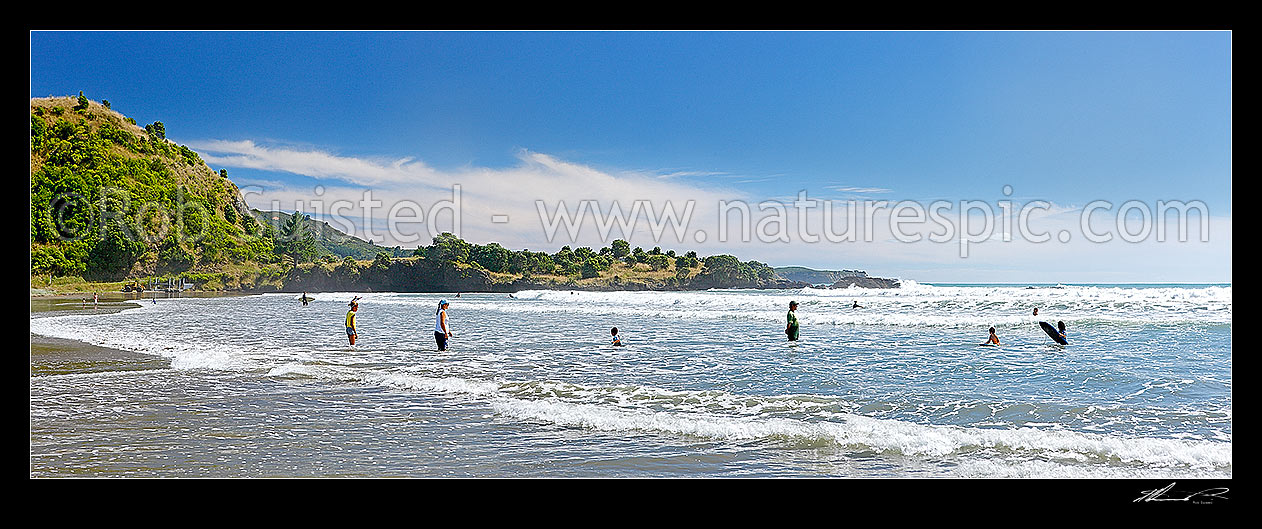 Image of Onepoto Bay and Beach with family swimming and bodyboarding in surf. Summertime panorama, Hicks Bay, Gisborne District, Gisborne Region, New Zealand (NZ) stock photo image