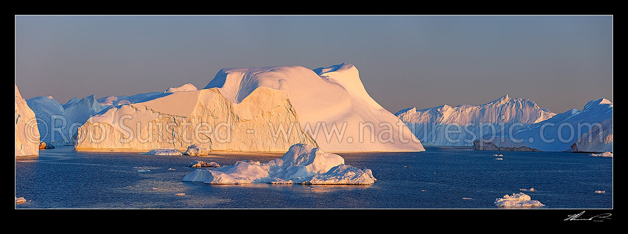 Image of Ilulissat Icefjord, giant icebergs at entrance to Ilulissat Kangerlua after leaving the Jakobshavn Isbr glacier. Sunset boat panorama, Ilulissat, Greenland stock photo image