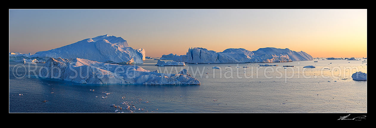 Image of Ilulissat Icefjord, giant icebergs at entrance to Ilulissat Kangerlua after leaving the Jakobshavn Isbr glacier. Sunset boat panorama, Ilulissat, Greenland stock photo image