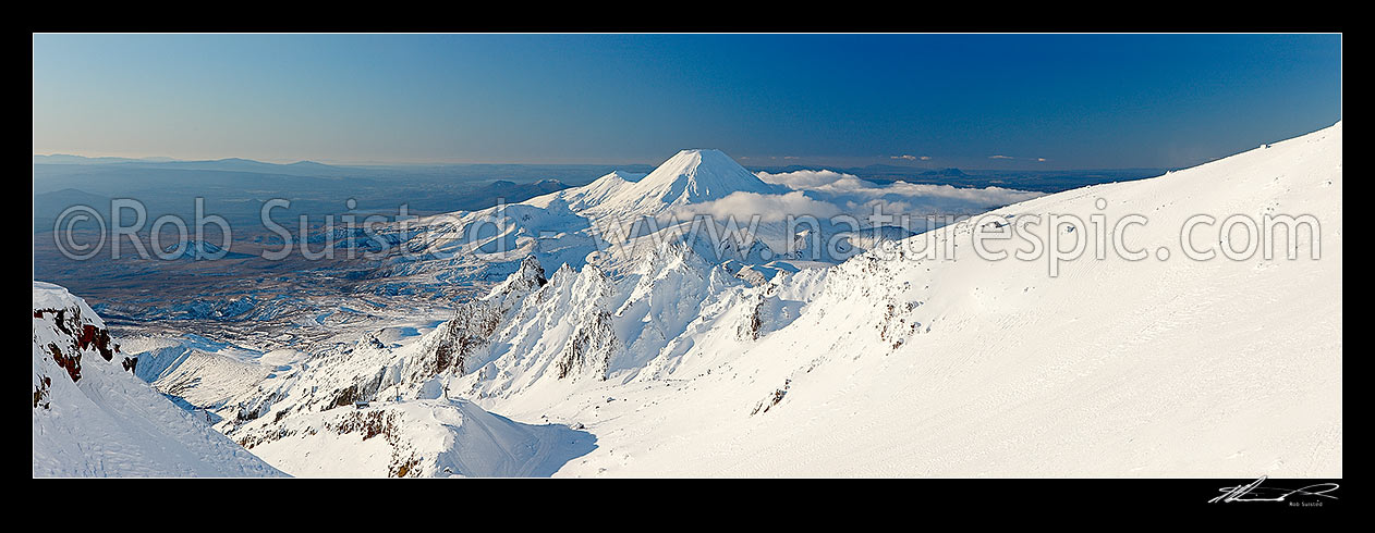 Image of Mount Ngauruhoe (2287m) from Mt Ruapehu. Pinnacle Ridge in foreground, Tama Lakes mid ground and Mt Tongariro (1967m) and Lake Taupo behind. Heavy winter snow. Panorama, Tongariro National Park, Ruapehu District, Manawatu-Wanganui Region, New Zealand (NZ) stock photo image