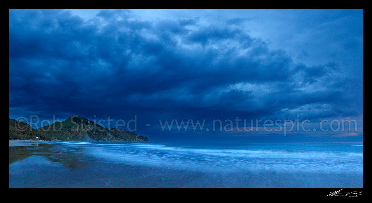 Image of Kaiaua Bay Beach moody twilight panorama, as storm clouds gather, with Marau Point left. Waves breaking on beach blurred in movement, Tolaga Bay, Gisborne District, Gisborne Region, New Zealand (NZ) stock photo image