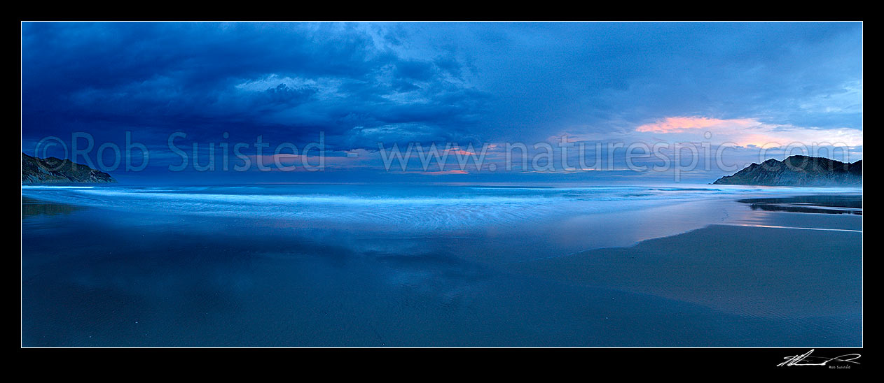 Image of Kaiaua Bay Beach moody sunset panorama, as storm clouds gather, with Marau Point left and Te Karaka Point right. Waves blurred by movement, Tolaga Bay, Gisborne District, Gisborne Region, New Zealand (NZ) stock photo image