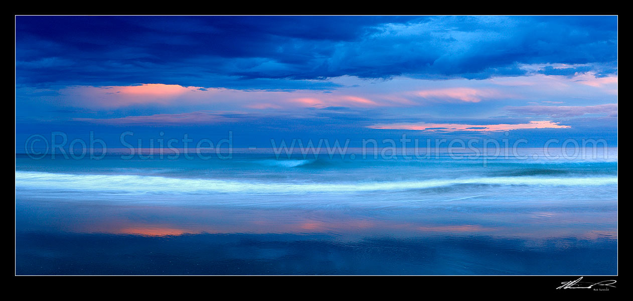 Image of Kaiaua Bay Beach moody panorama, as storm clouds gather at sunset. Waves breaking on beach blurred in movement, Tolaga Bay, Gisborne District, Gisborne Region, New Zealand (NZ) stock photo image