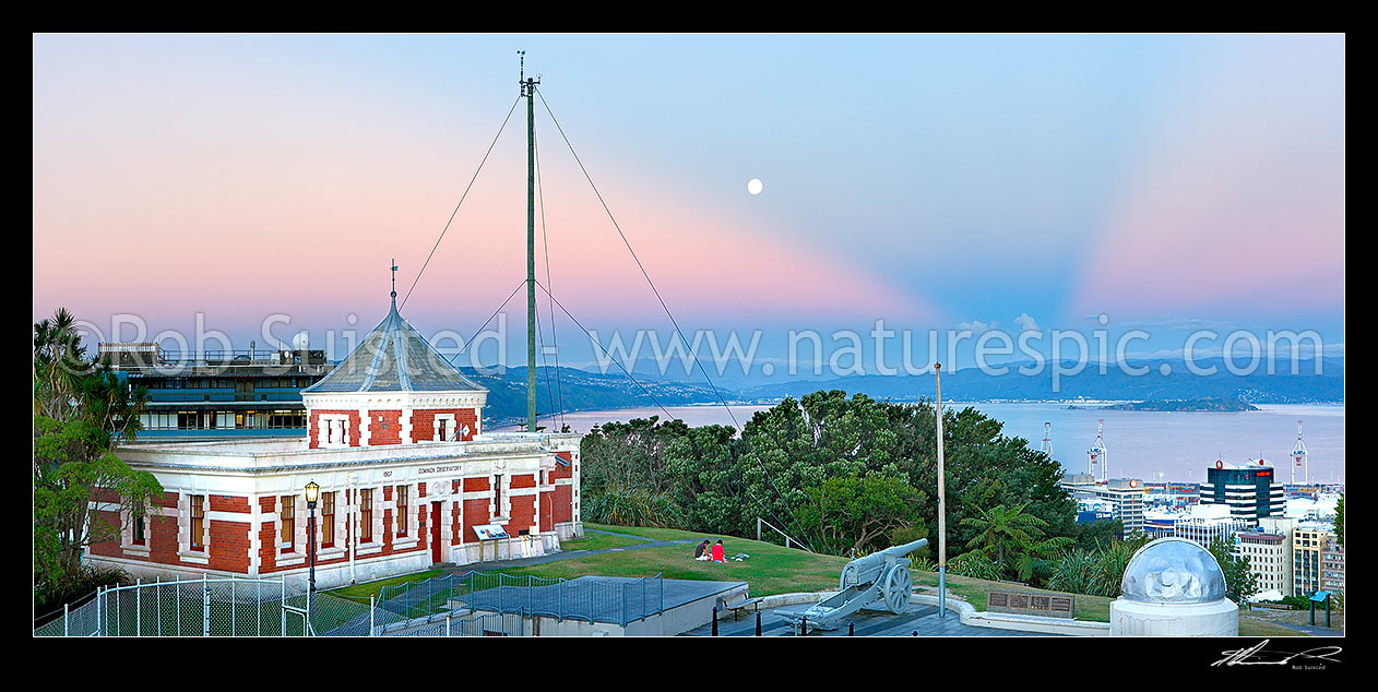 Image of Historic Dominion Observatory built 1907 in Edwardian Baroque style to house the time service. The Krupp gun and Garden Battery to right. Panorama over harbour at dusk with moonrise, Wellington, Wellington City District, Wellington Region, New Zealand (NZ) stock photo image