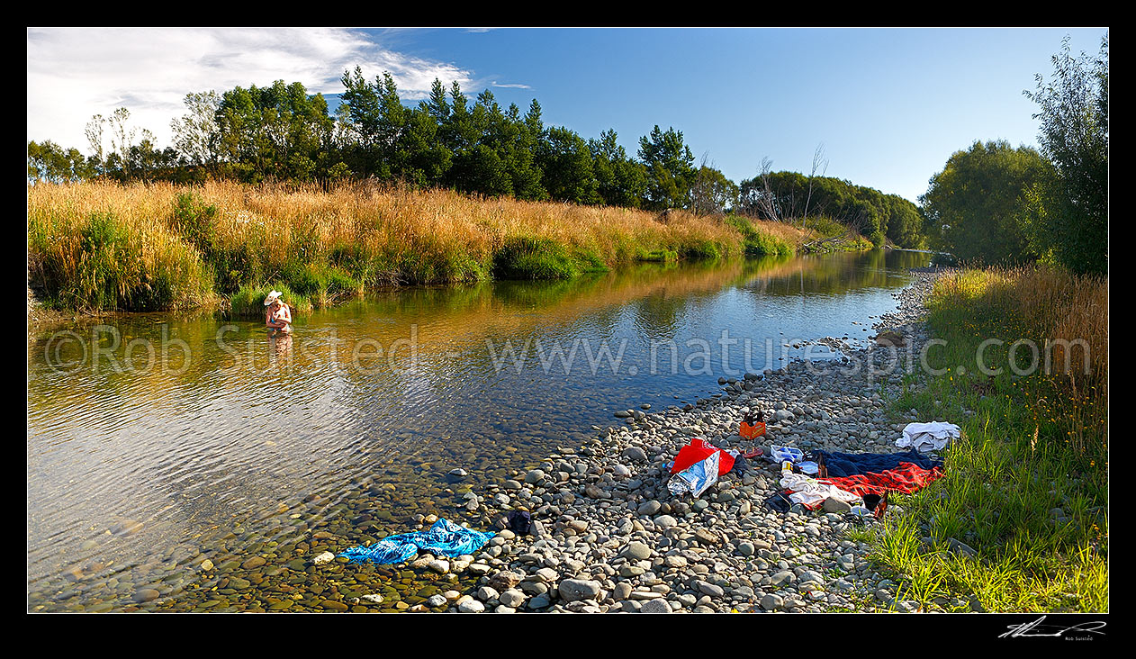 Image of Mother and baby enjoying summer river swimming and picnic in late afternoon. Panorama, Te Anau, Southland District, Southland Region, New Zealand (NZ) stock photo image