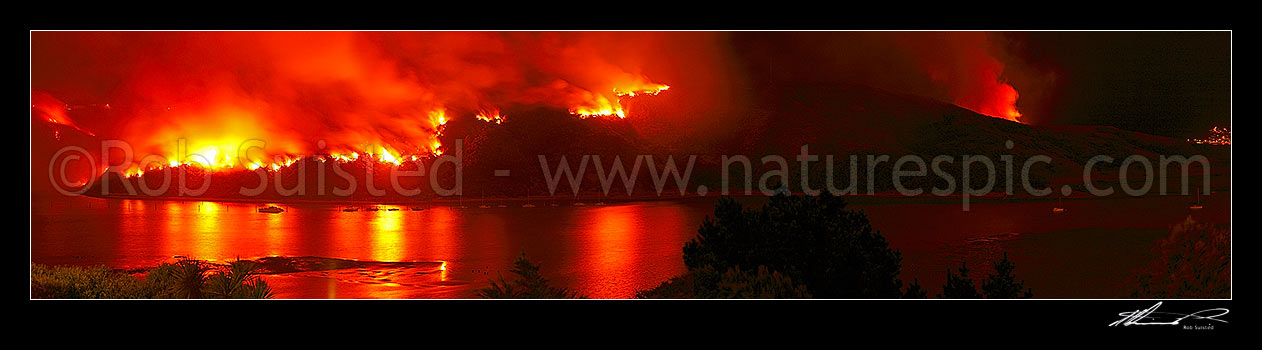 Image of Giant wild bushfire on the Titahi Bay Peninsula with Yachts and Porirua Harbour in foreground. Onepoto and Gloaming Hill left, Plimmerton far right. Nighttime panorama, Titahi Bay, Porirua City District, Wellington Region, New Zealand (NZ) stock photo image