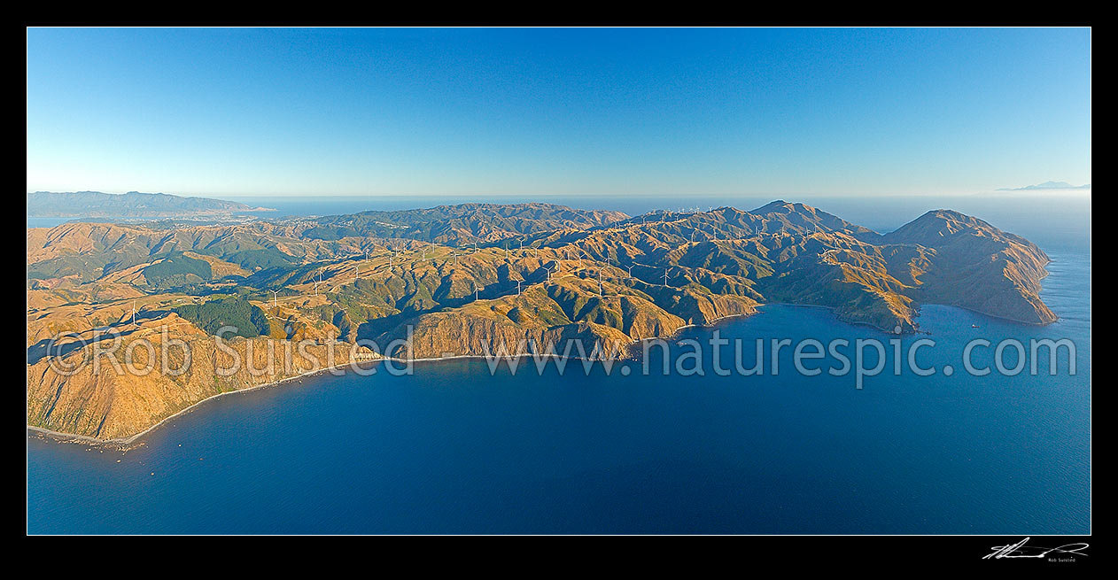 Image of Meridian Energys Project West Wind farm of 62 turbines at Terawhiti Station and Makara Farm west of Wellington. Opau bay left, Cape Terawhiti, Te Ikaamaru and Ohau Bays right. Wellington far left. Kaikoura Ranges far right, Makara Beach, Wellington City District, Wellington Region, New Zealand (NZ) stock photo image