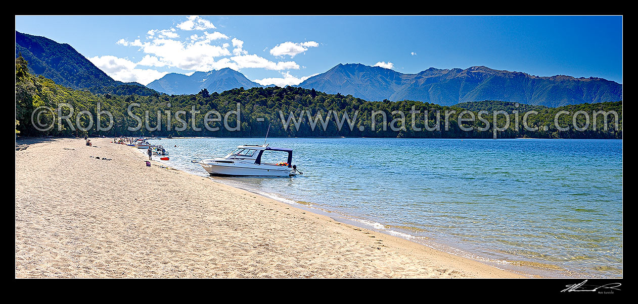 Image of Lake Te Anau at Brod Bay with people enjoying summertime boating and picnics on the beach. Murchison Mountains beyond, Te Anau, Southland District, Southland Region, New Zealand (NZ) stock photo image