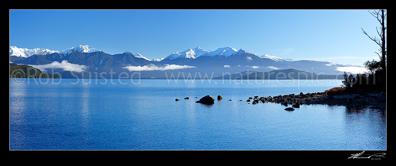 Image of Lake Manapouri morning winter calm. Kepler Moutains and track under snow centre. Panorama, Te Anau, Fiordland National Park, Southland District, Southland Region, New Zealand (NZ) stock photo image