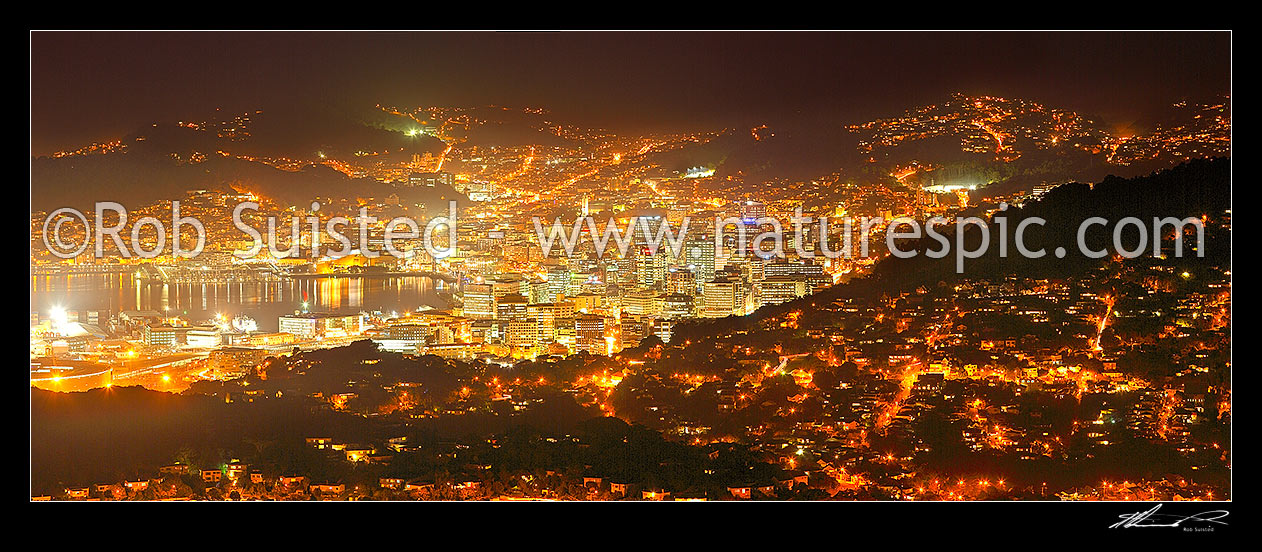 Image of Wellington City at night. Central business district (CBD), buildings, harbour and suburbs glowing with lights after dark. Panorama, Wellington, Wellington City District, Wellington Region, New Zealand (NZ) stock photo image