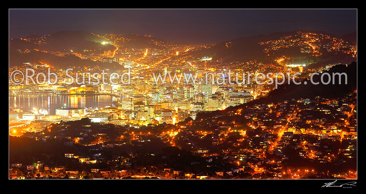 Image of Wellington City at night. Central business district (CBD), buildings, harbour and suburbs glowing with lights after dark. Panorama, Wellington, Wellington City District, Wellington Region, New Zealand (NZ) stock photo image