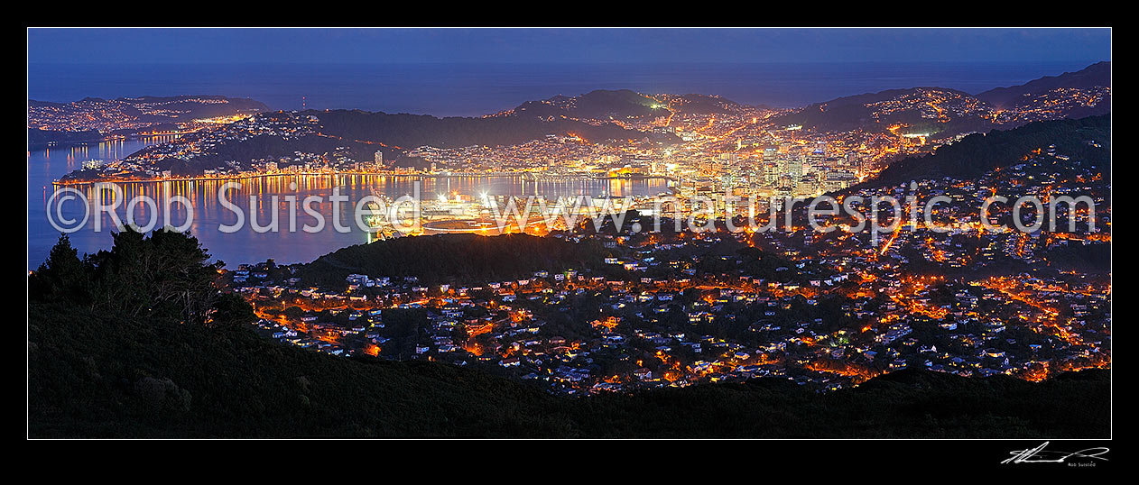 Image of Wellington City at night. Central business district (CBD), buildings, harbour and suburbs glowing with lights after dark. Panorama, Wellington, Wellington City District, Wellington Region, New Zealand (NZ) stock photo image