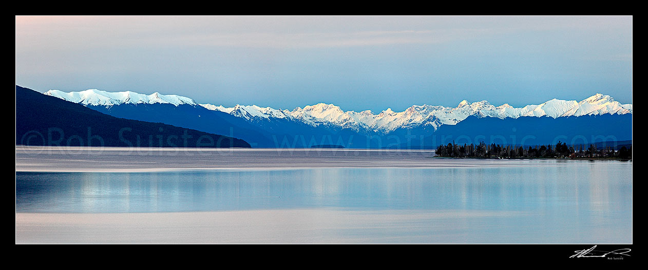 Image of Lake Te Anau panorama from the southern end. Te Anau township far right, snow capped Fiordland Mountains and National Park distant, Te Anau, Southland District, Southland Region, New Zealand (NZ) stock photo image