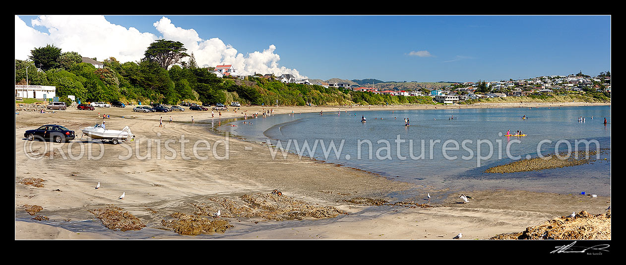 Image of Titahi Bay beach with swimmers and summer visitors. Boat launching near boatsheds. Panorama, Titahi Bay, Porirua City District, Wellington Region, New Zealand (NZ) stock photo image