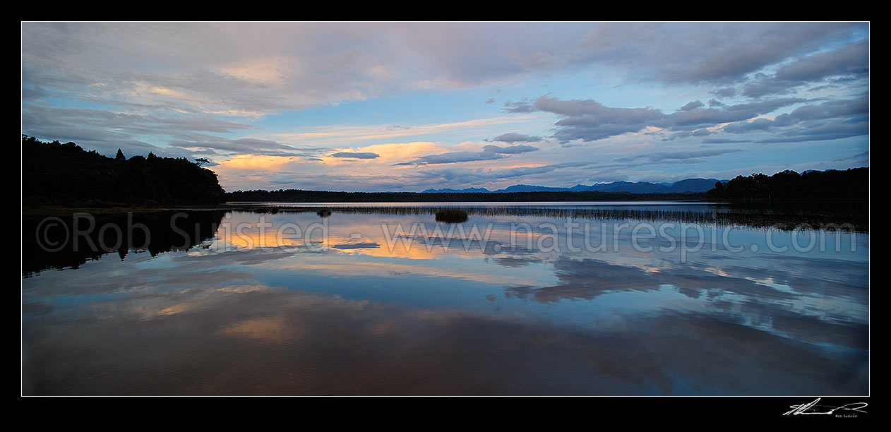 Image of Lake Mahinapua sunset over calm lake waters and reflection of clouds. Panorama, Hokitika, Westland District, West Coast Region, New Zealand (NZ) stock photo image