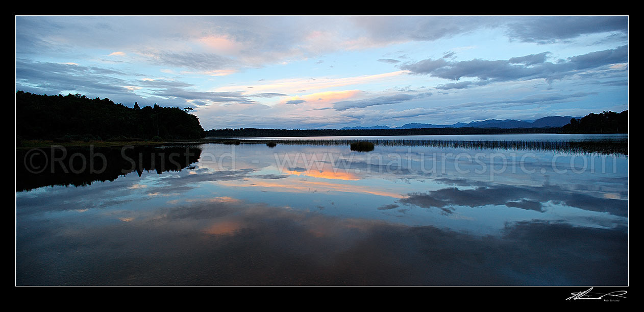 Image of Lake Mahinapua sunset over calm lake waters and reflection of clouds. Panorama, Hokitika, Westland District, West Coast Region, New Zealand (NZ) stock photo image