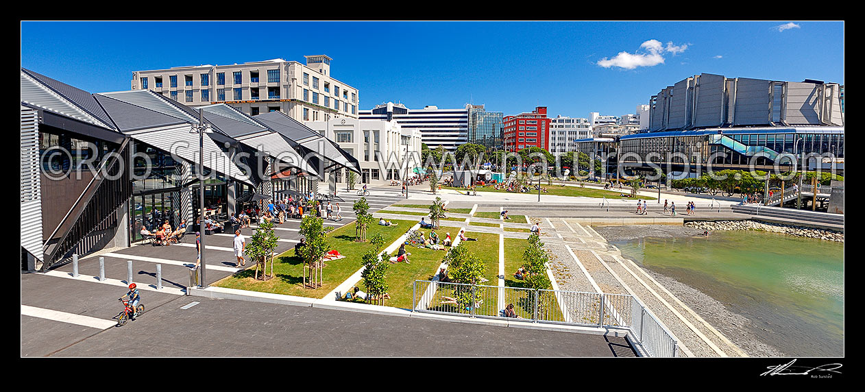 Image of Wharewaka o Poneke building on Wellington Waterfront and lagoon, and people enjoying a summers day. Michael Fowler Centre right. Panorama, Wellington, Wellington City District, Wellington Region, New Zealand (NZ) stock photo image