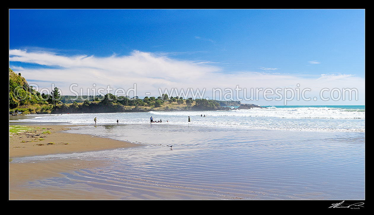 Image of Onepoto Bay and Beach with people and family swimming and bodyboarding in surf. Summertime, Hicks Bay, Gisborne District, Gisborne Region, New Zealand (NZ) stock photo image