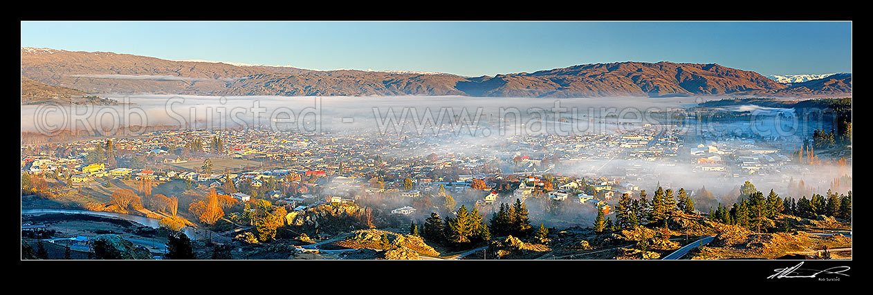 Image of Alexandra township under morning mist on a frosty winter morning, with Manuherikia River in foreground. Panorama, Alexandra, Central Otago District, Otago Region, New Zealand (NZ) stock photo image