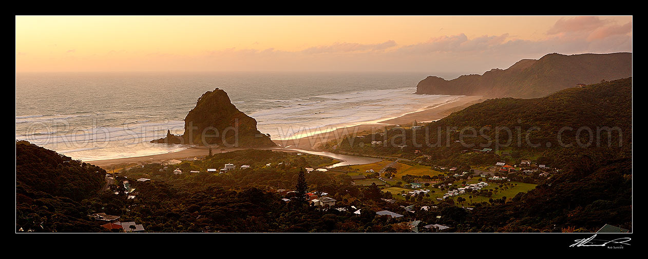 Image of Piha Beach with Lion Rock prominent in the small seaside village surrounded by the Waitakere ranges at sunset. Te Waha Point and Kohunui Bay distant. Panorama, Piha Beach, Auckland, Waitakere City District, Auckland Region, New Zealand (NZ) stock photo image