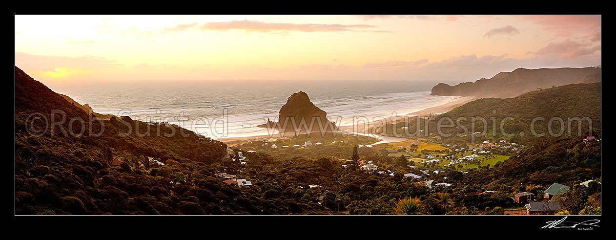 Image of Piha Beach with Lion Rock prominent in the small west coast village surrounded by the Waitakere ranges at sunset. Te Waha Point and Kohunui Bay distant. Panorama, Piha Beach, Auckland, Waitakere City District, Auckland Region, New Zealand (NZ) stock photo image