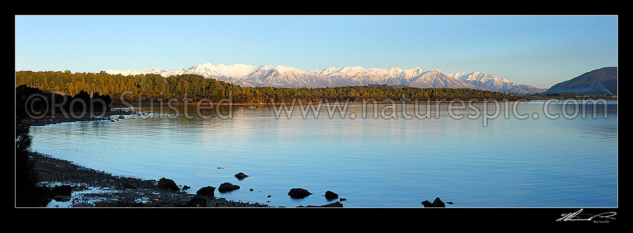 Image of Lake Manapouri panorama looking towards to snowy Takitimu Mountains range in winter. Manapouri township far right, Manapouri, Southland District, Southland Region, New Zealand (NZ) stock photo image