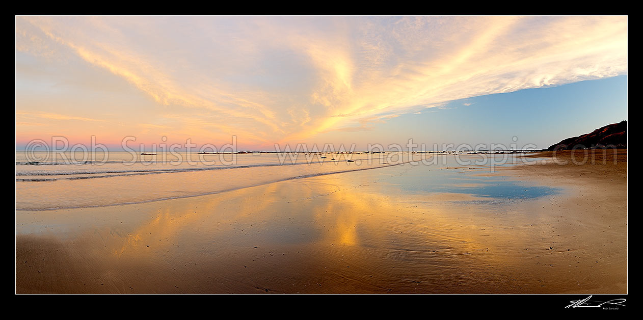 Image of Golden wispy sunest clouds reaching across sky and reflecting in beach sands of Port Awanui. Panorama, Port Awanui, East Coast, Gisborne District, Gisborne Region, New Zealand (NZ) stock photo image