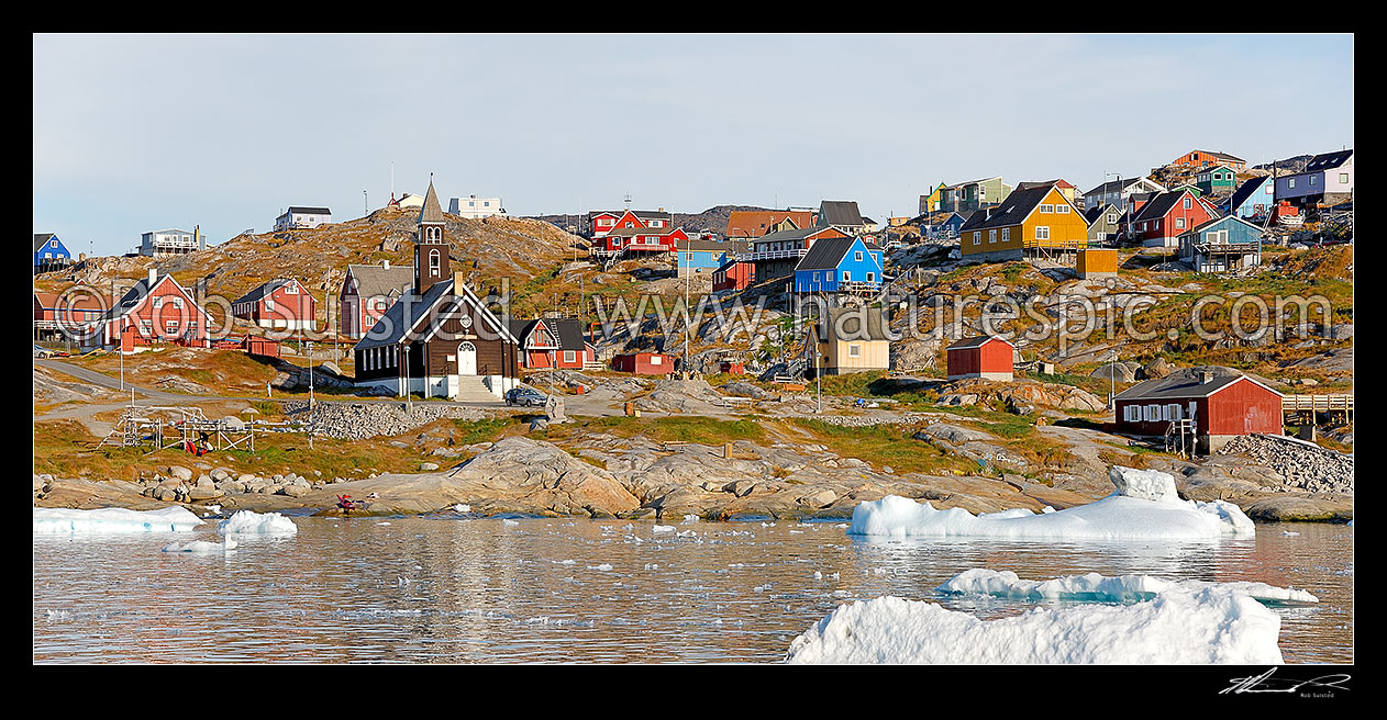 Image of Ilulissat township seen from the sea, with Zion's church (1779) prominent in the bay, with bright coloured houses on hills. Panorama, Ilulissat, Greenland stock photo image