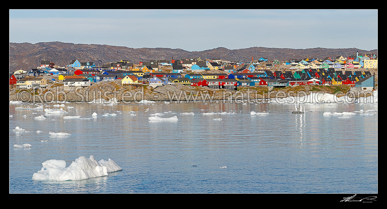 Image of Ilulissat township seen from the sea, with bright coloured houses on hills with ice floating in water from Jakobshavn Isbr (Jakobshavn Glacier). Panorama, Ilulissat, Greenland stock photo image