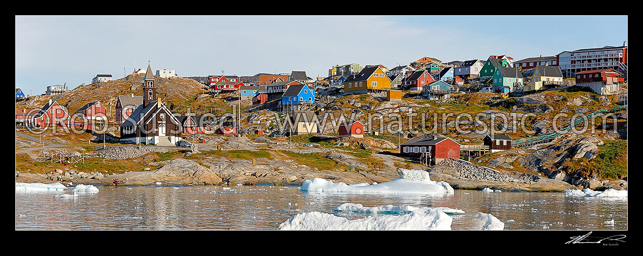 Image of Ilulissat township seen from the sea, with Zion's church (1779) prominent in the bay, with bright coloured houses on hills. Panorama, Ilulissat, Greenland stock photo image