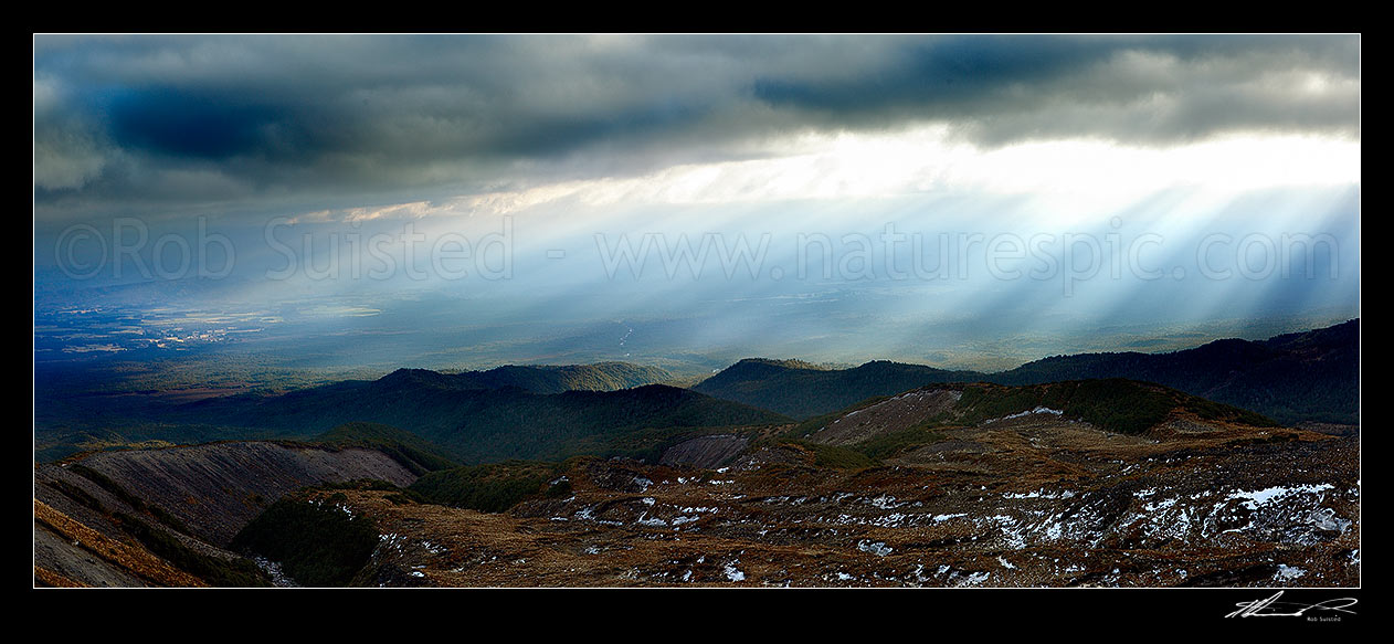 Image of Ohakune (far left), farmland and flanks of Mount Ruapehu being lit by sun shafts behind a passing weather front. Maungaturuturu, Makotuku Rivers. Panorama, Tongariro National Park, Ruapehu District, Manawatu-Wanganui Region, New Zealand (NZ) stock photo image