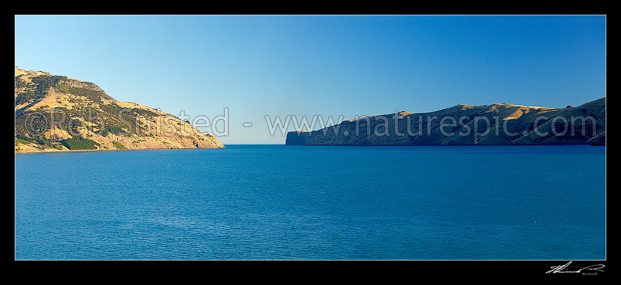 Image of Akaroa Harbour entrance and heads in late afternoon light. Timutimu head and Lucas Peak at centre right. Banks Peninsula. Panorama, Akaroa, Christchurch City District, Canterbury Region, New Zealand (NZ) stock photo image