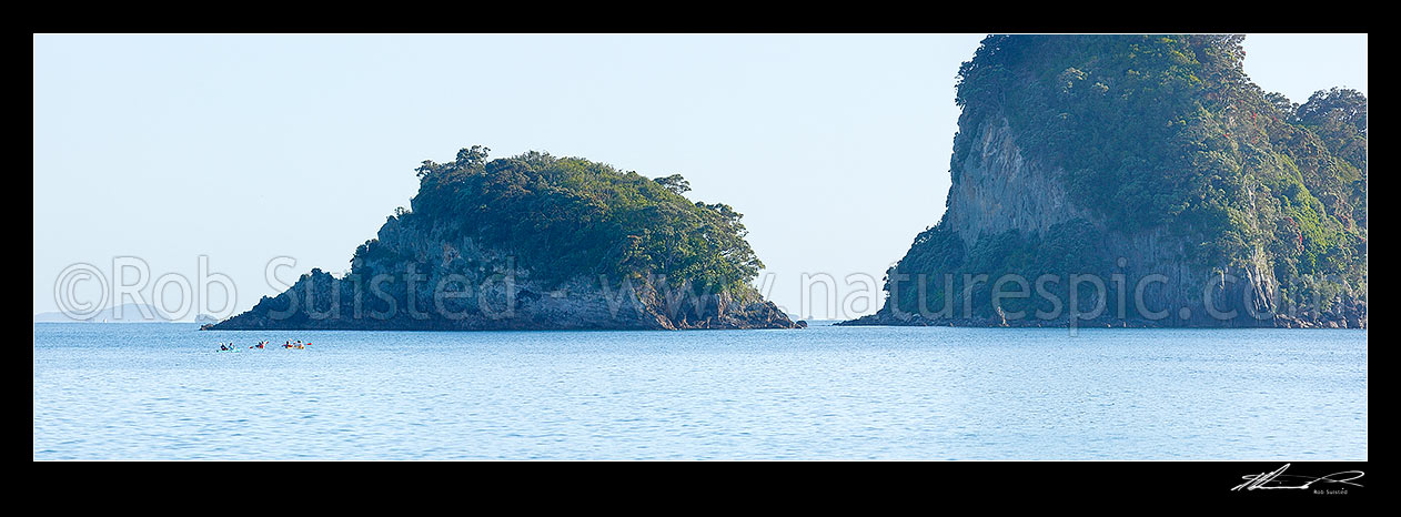 Image of Sea kayakers in Whanganui A Hei Marine Reserve, with Poikeke and Motueka (Pigeon) Islands behind. Cathedral Cove. Panorama, Hahei, Coromandel Peninsula, Thames-Coromandel District, Waikato Region, New Zealand (NZ) stock photo image