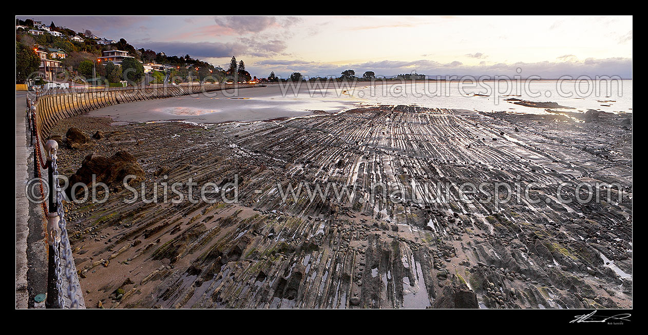 Image of Tahunanui Beach evening sunset panorama with dramatic geologial rock patterns in foreground, Nelson, Nelson City District, Nelson Region, New Zealand (NZ) stock photo image