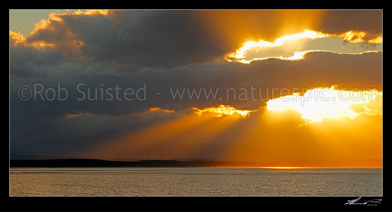 Image of Dramatic sunset, rays of light and clouds over Tasman Bay and Rabbit Island, from Tahunanui Beach, Nelson, Nelson City District, Nelson Region, New Zealand (NZ) stock photo image