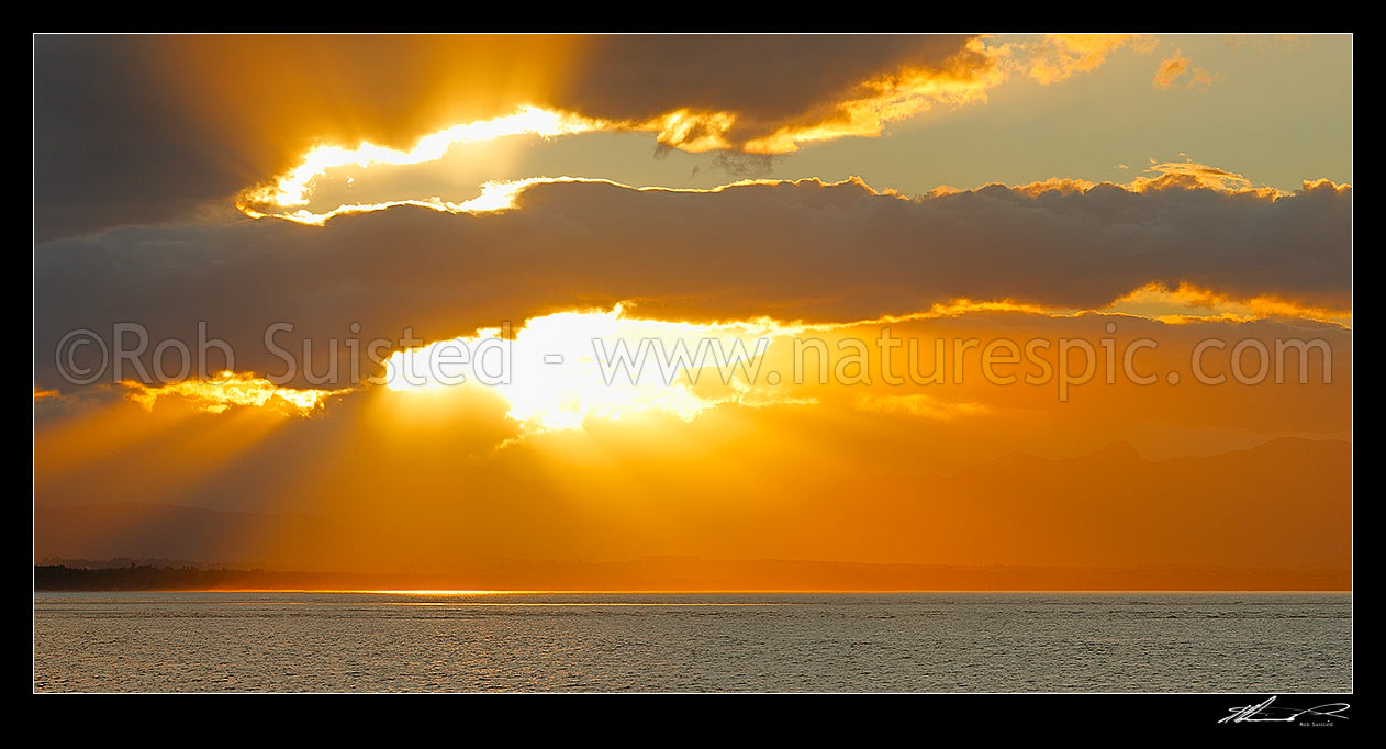 Image of Dramatic sunset, rays of light and clouds over Tasman Bay and Rabbit Island, from Tahunanui Beach, Nelson, Nelson City District, Nelson Region, New Zealand (NZ) stock photo image