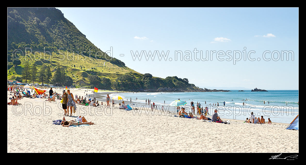 Image of Mount Maunganui beach panorama, with people sunbathing and swimming. The Mount peak at left, Mount Maunganui, Tauranga District, Bay of Plenty Region, New Zealand (NZ) stock photo image