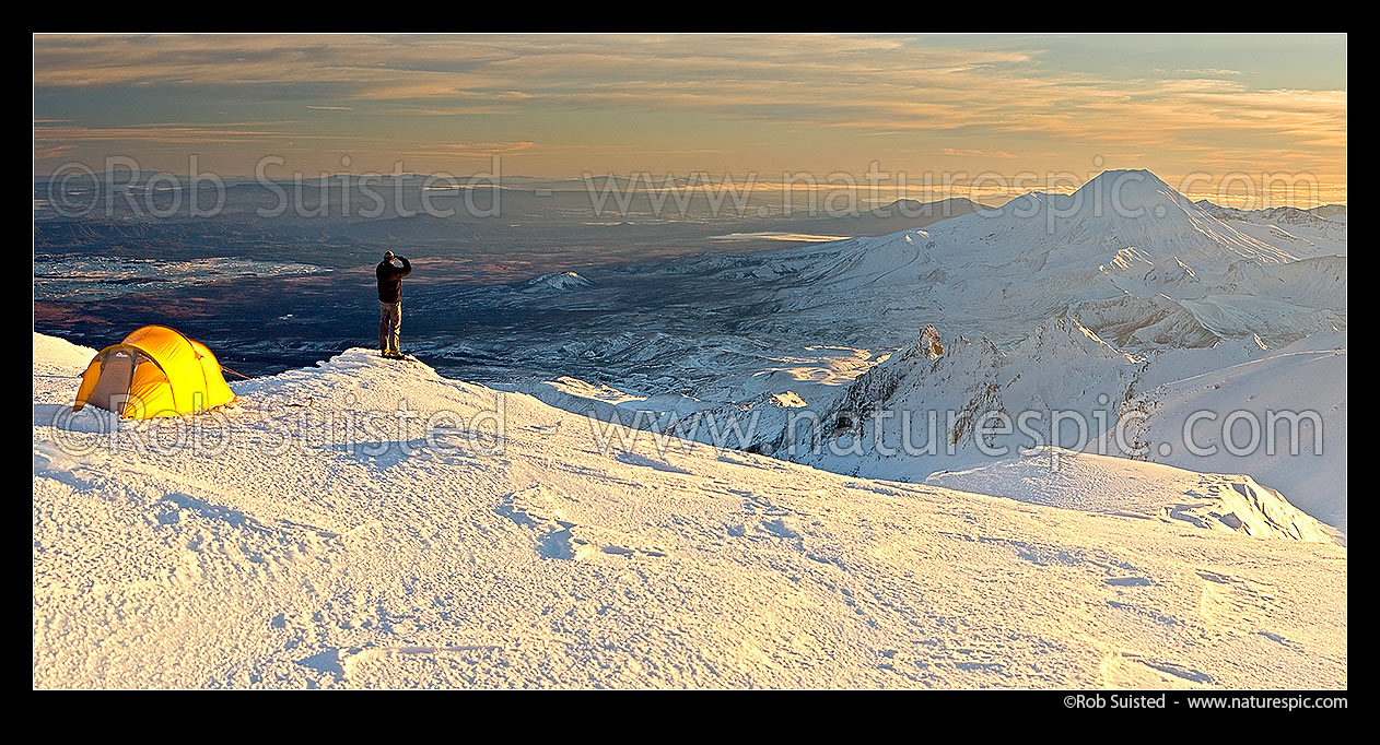 Image of Mount Ngauruhoe sunrise (2287m) from alpine tent camp near summit of Mt Ruapehu. Mt Tongariro (1967m) and Lake Taupo behind. Heavy winter snow. Panorama, Tongariro National Park, Ruapehu District, Manawatu-Wanganui Region, New Zealand (NZ) stock photo image