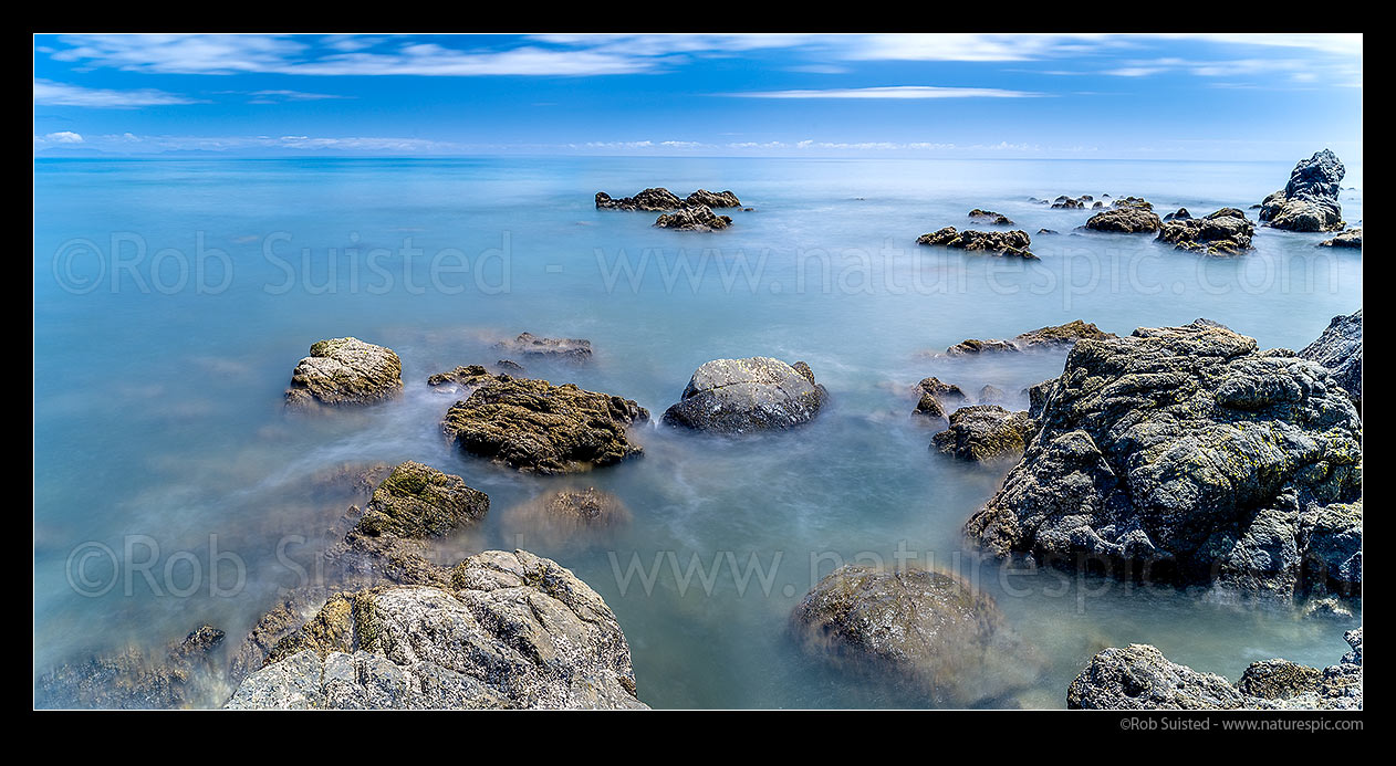 Image of Cook Strait seen from Pukerua Bay roacky coastline. Ethereal blurring of seawater and waves. South Island visible distant left. Panorama, Pukerua Bay, Porirua City District, Wellington Region, New Zealand (NZ) stock photo image