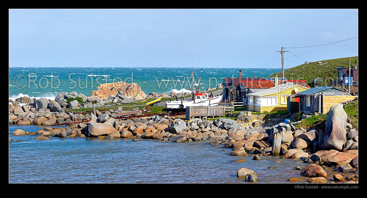 Image of Cosy Nook village nestled into a natural harbour on the Southen Scenic Route near Colac Bay. Small historic fishing village with cribs / baches. Panorama, Cosy Nook, Southland District, Southland Region, New Zealand (NZ) stock photo image