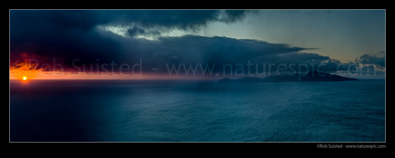 Image of Kapiti Island sunset with sleety rain showers moving in from Cook Strait on a very moody evening. Rauoterangi Chanel (Otaheke Strait) at right. Panorama, Paekakariki, Kapiti Coast District, Wellington Region, New Zealand (NZ) stock photo image