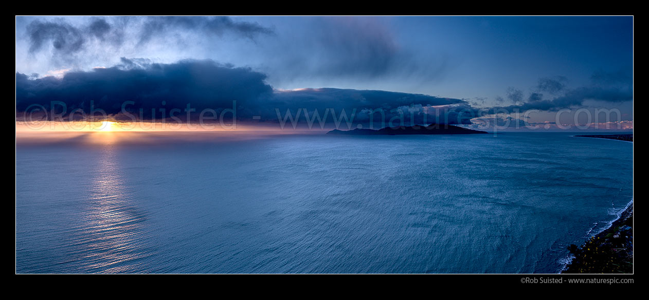 Image of Kapiti Island Nature Reserve and moody dramatic sunset with sleety rainshowers coming off Cook Strait. Paraparaumu far right. Panorama, Paekakariki, Kapiti Coast District, Wellington Region, New Zealand (NZ) stock photo image