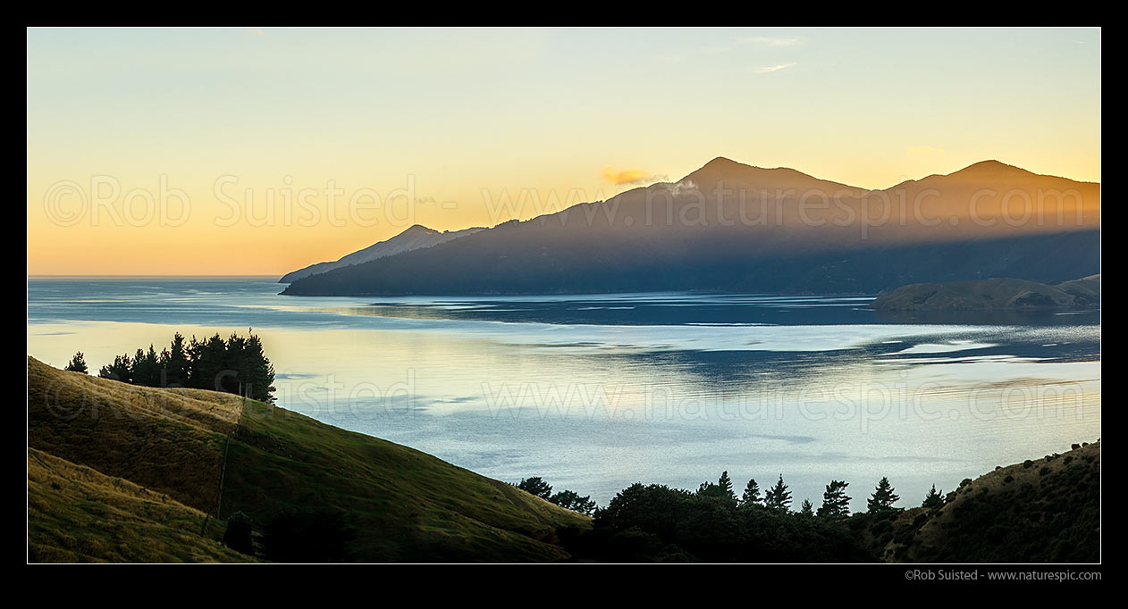 Image of Admiralty Bay sunrise panorama in Marlborough Sounds. Sunshafts over Puketea Bay and Matatoko Point. Trio Islands (Kuru Pongi) far left, French Pass, Marlborough Sounds, Marlborough District, Marlborough Region, New Zealand (NZ) stock photo image