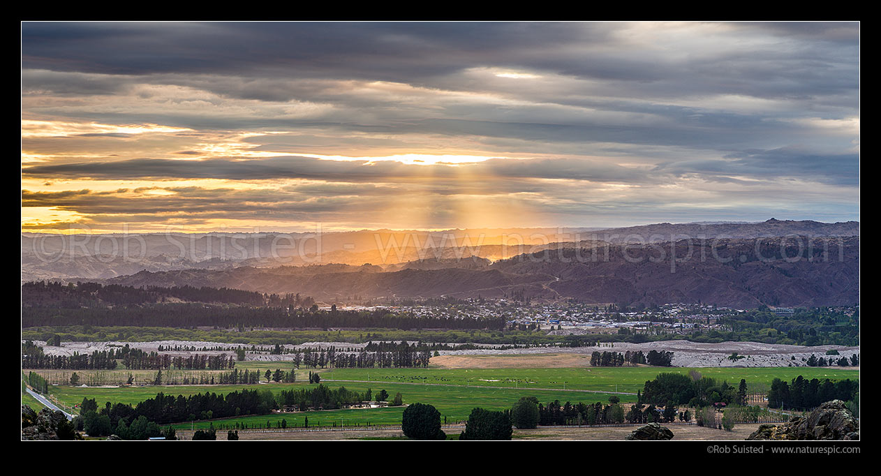 Image of Alexandra town bathed in sunrise crepuscular rays. Seen from Earnscleugh. Panorama, Alexandra, Central Otago District, Otago Region, New Zealand (NZ) stock photo image